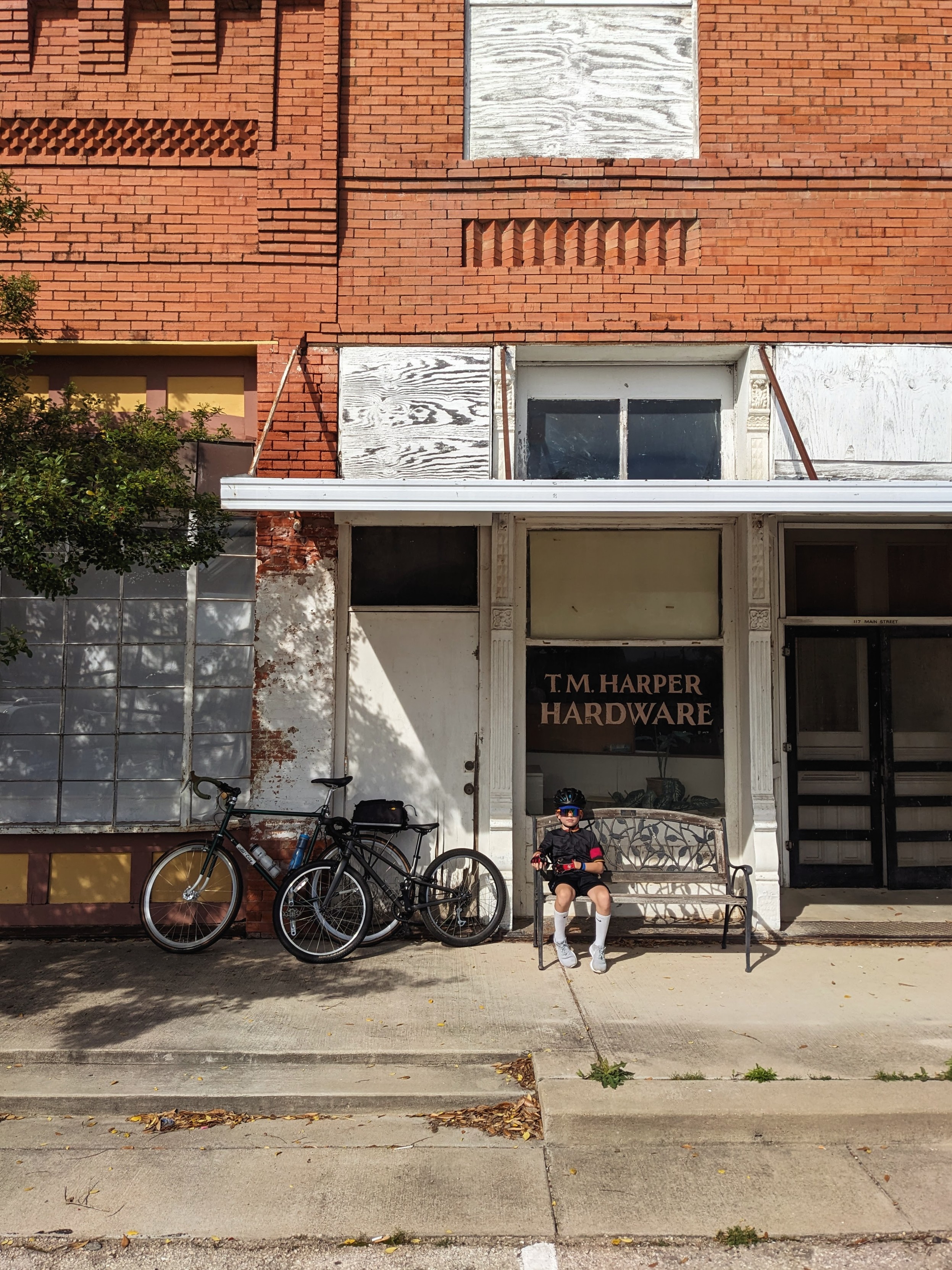 Boy sitting in front of an abandoned store, "T.M. Harper Hardware"