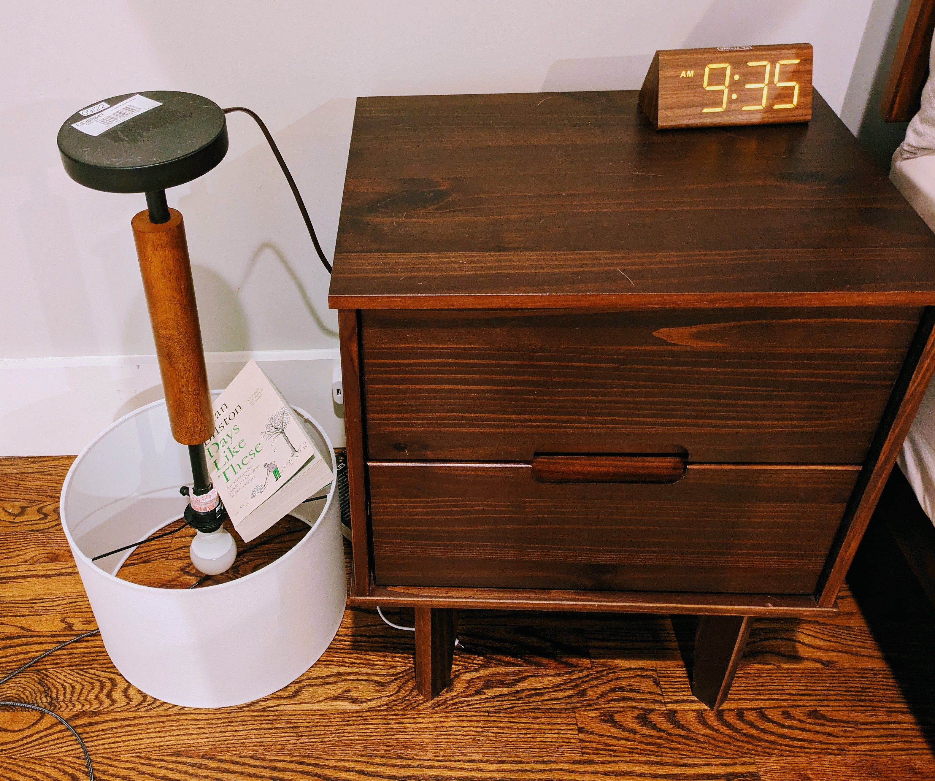A nightstand with a upside down lamp on the floor next to it 