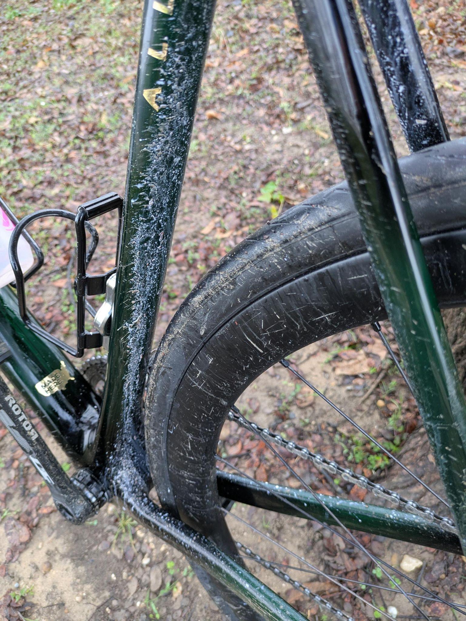 close-up of a bicycle rear tire and rear triangle. The rear triangle, especially the seat tube, is covered in tubeless tire sealant.