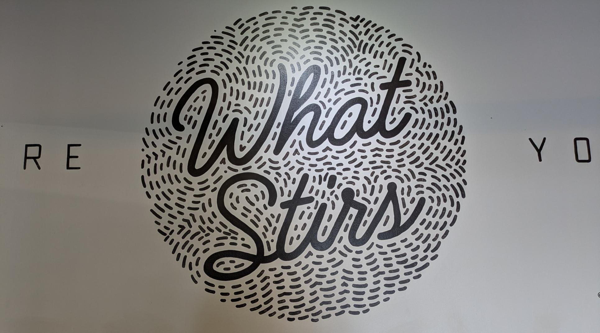 Black and white mural "Share what stirs you". "Share" and "you" are both partially out of frame