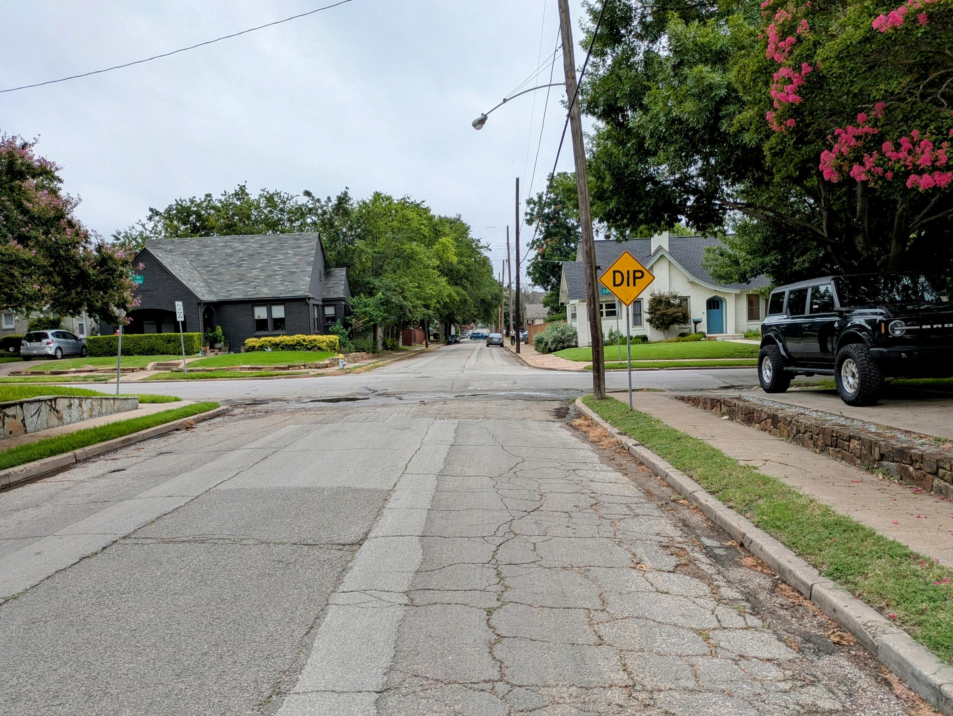 A street with a "Dip" road sign. The font/style of the Dip sign is different than the other one